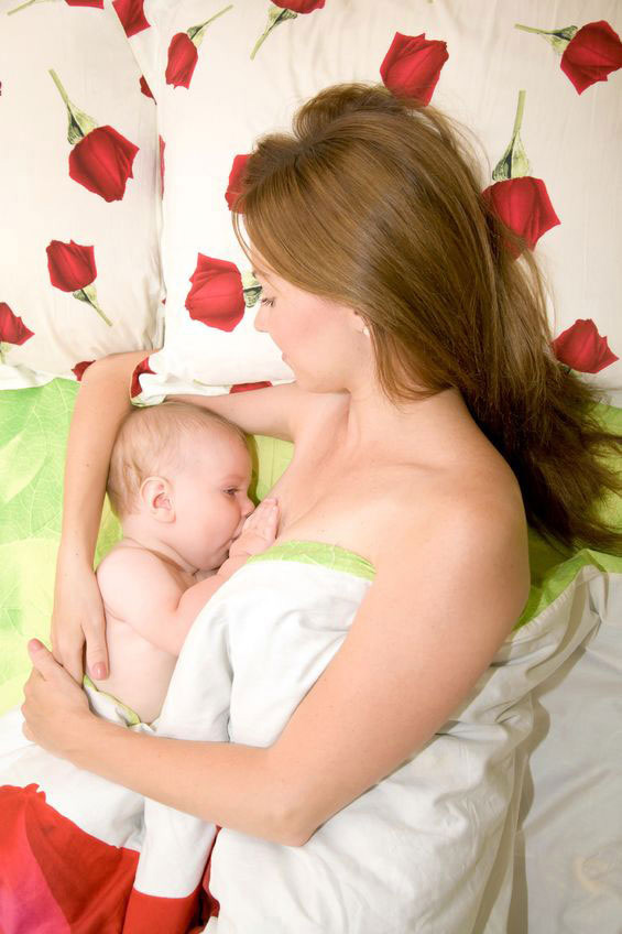 mother lies on bed to breastfeed