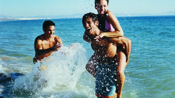 Девушка и два молодых человека купаются в море