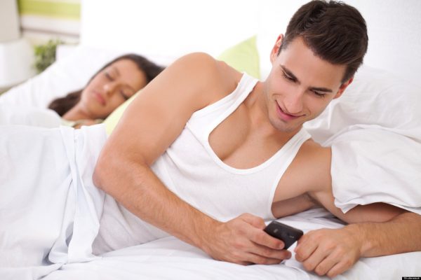 Мужчина с телефоном лежит в кровати